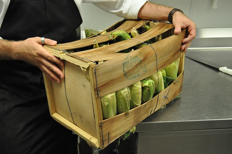 A chef at Table 100 unpacks fresh corn, purchased at a local farmers market.
