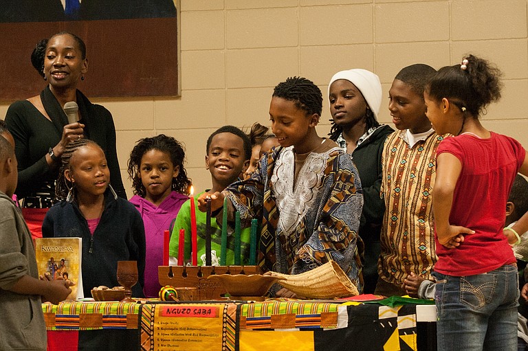 Local children gather to light the Kwanzaa candles at the Medgar Evers Community Center Thursday night.