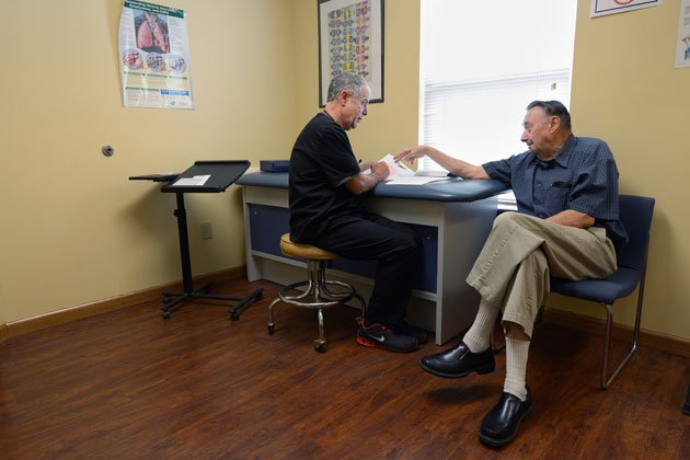 Dr. Daniel J. Hurley (left) talks to patient William Sanders (right) at his outpatient clinic in Beech Grove, Indiana. Hurley was credited with writing more than 160,000 prescriptions in Medicare Part D in 2010, the most of any provider in the country. Hurley said prescriptions by others in his practice were credited to him by nursing home pharmacies, but that Medicare has never asked him about his numbers. “Why wouldn’t they call us up and ask us?” he said.