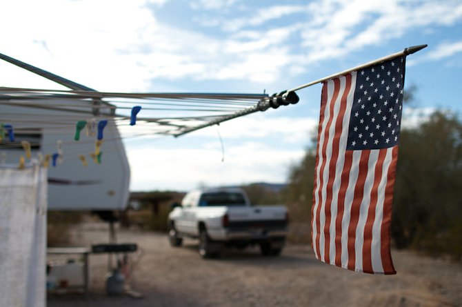 A flag flies on a clothesline outside an RV home in the American Southwest. An American expatriate, living in Paris, warns of an increasing disconnect between America's ideals and actions.