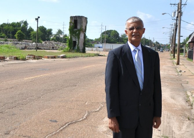 Mayor Chokwe Lumumba stands out outside his former law office on Mill Street, a bumpy potholed road and favorite dumpsite, in June 2103. City officials hope a citywide beautification effort will spruce up areas like those along Mill Street.