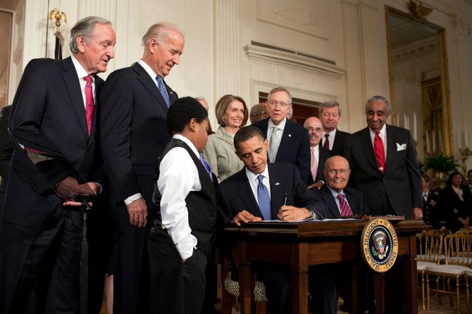 President Obama signing the health insurance initiative into law.