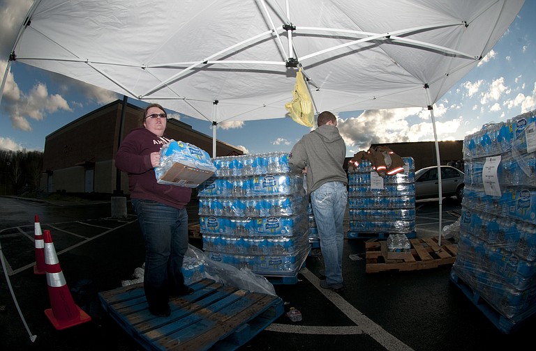 Bethany Whisman and Blake Kenney, both of Poca, W.Va., volunteer by handing out cases of bottled water to those affected by the Elk River water contamination on Jan. 11, 2014, at Poca High School, Poca, W.Va. Residents of Kanawha, Boone, Putnam, Lincoln, Logan, Clay, Roane and Jackson counties were told to stop using tap water after a chemical leak contaminated the West Virginia American Water company’s system in those areas.