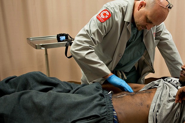 Dr. Andrew Dennis, a surgeon in the Cook County hospital trauma unit, looks at the wound of a man who was shot in 2012 in Chicago, on May 16, 2013. Americans in violent neighborhoods are developing PTSD at rates similar to combat veterans.