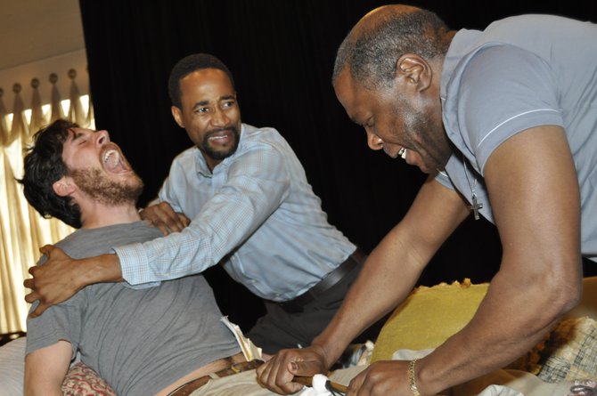 At rehearsals for New Stage Theatre’s production of the “The Whipping Man,” Yohance Myles’ character John holds Brian Maxsween’s character, Caleb, back as Simon, played by Jay Unger, dresses Caleb’s wounded leg.