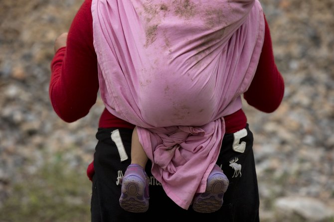 On June 20, 2014, a Central American migrant carrying a small child waits alongside a stuck northbound freight train, outside Reforma de Pineda, Chiapas state, Mexico.