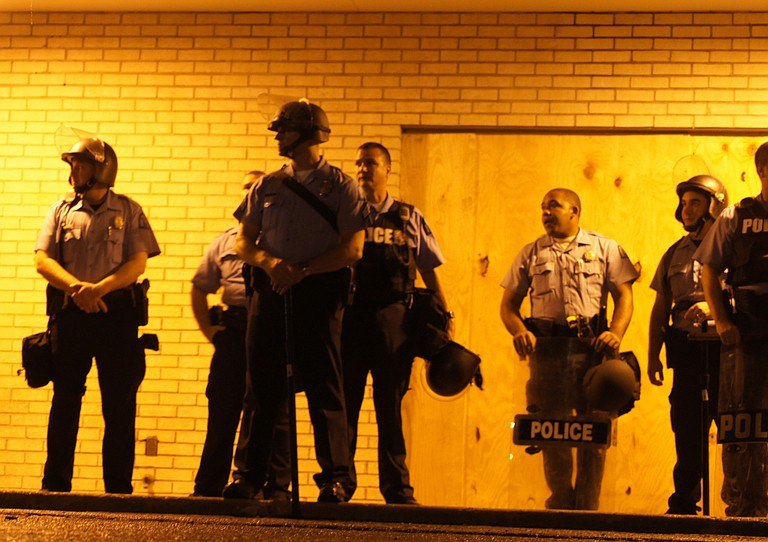 Members of the St. Louis Police Department stand by on the first night of a a curfew that Missouri Gov. Jay Nixon ordered.  Approximately 15 law-enforcement agencies were called to assist during protests.
