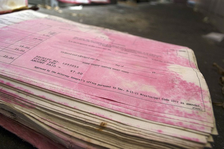 Pages of history have turned pink after water damage caused the red cover to bleed onto the book’s pages.