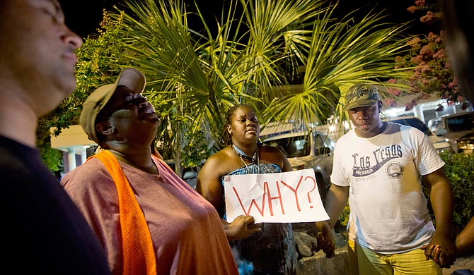 Surreace Cox, of North Charleston, S.C., holds a sign during a prayer vigil down the street from the Emanuel AME Church early Thursday, June 18, 2015, following a shooting Wednesday night in Charleston, S.C. Photo courtesy Associated Press/David Goldman