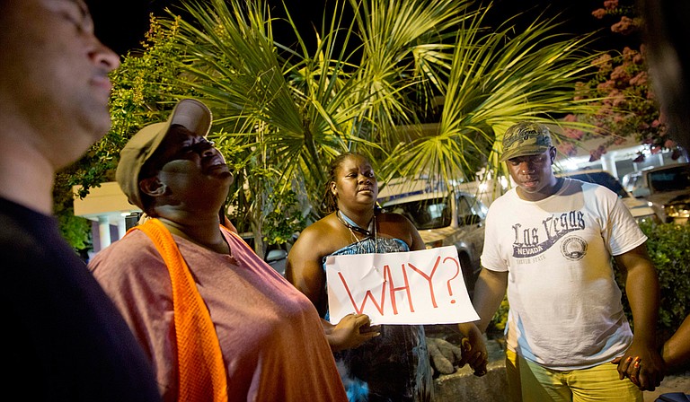Surreace Cox, of North Charleston, S.C., holds a sign during a prayer vigil down the street from the Emanuel AME Church early Thursday, June 18, 2015, following a shooting Wednesday night in Charleston, S.C. Photo courtesy Associated Press/David Goldman