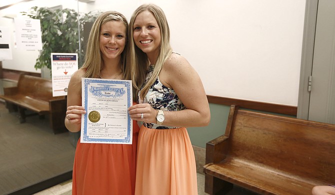 Tiffany Brosh (right) and Laurin Locke (left) pose with their marriage license at the Hinds County Courthouse on Monday after being denied their right to marry on Friday morning.