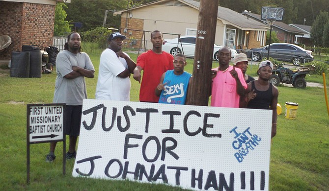 Friends of 39-year-old Jonathan Sanders, who died on July 8 after encountering a white police officer, gather around one of several memorials erected in Sanders' memory.  