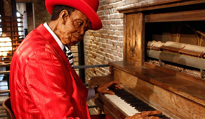 Blues musician Pinetop Perkins plays an old vertical piano.