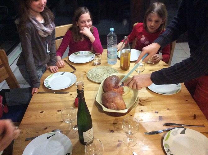 (Left to right) Alix Schmitt, Denver Coupe and Eleonore Schmitt watch as André Schmitt carves the estomac de porc farci. Photo courtesy R.H. Coupe