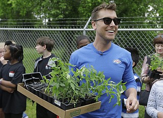 Lance Bass helps students plant seedlings in a community garden in Clinton.