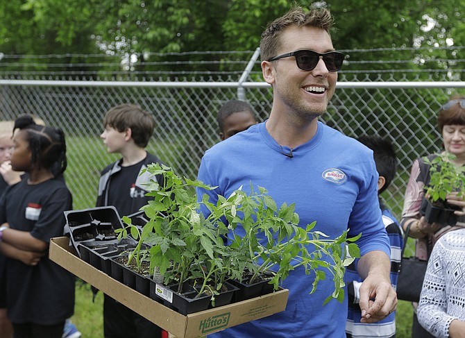 Lance Bass helps students plant seedlings in a community garden in Clinton.