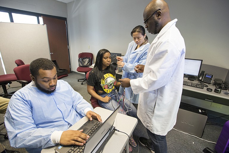 Byron D’Andra Orey (right), a JSU political science professor, is conducting experiments to examine unconscious bias in African Americans. Seated at the computer is his son, Kalen Orey, who helps with the project, while JSU criminal-justice professor Yu Zhang wires up student Ananda Collins.