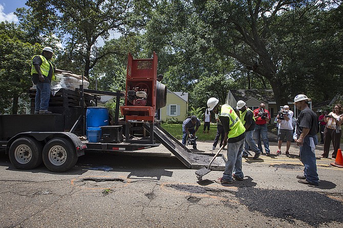 Workers for Gluckstadt-based Mega Technologies, LLC fill potholes on Northview Drive in Fondren. The potholes were marked with an orange circle. The company uses a polymer-based product rather than asphalt.