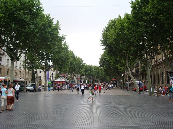 Las Ramblas, a street of stalls and shops that cuts through the center of Barcelona, is one of the city's top tourist destinations. People walk down a wide, pedestrian path in the center of the street but cars can travel on either side. Photo courtesy Flickr/Juan Pablo Ortiz Arechiga