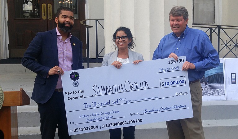 Mayor Chokwe Antar Lumumba presents a check to Salam Rida, Urban Designer with the City of Jackson's Long-Range Planning Division, who is accepting on behalf of Samantha Okolita of Brooklyn, N.Y. Okolita won the Unified Signage Competition. On the right is Ben Allen, president of Downtown Jackson Partners.
