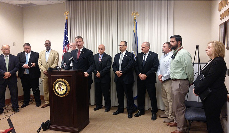 A federally organized drug task force arrested 11 people near Philadelphia, Miss., on May 30, U.S. Attorney Mike Hurst said at a press conference. Law enforcement personnel are standing behind him.