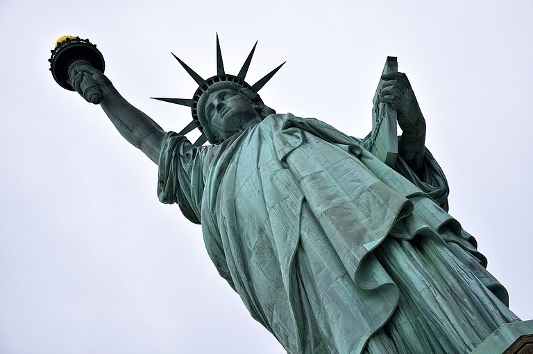 A protest against U.S. immigration policy forced the evacuation of the Statue of Liberty on the Fourth of July, with a group unfurling a banner from the pedestal and a woman holding police at bay for hours after she climbed the base and sat by the statue's robes.