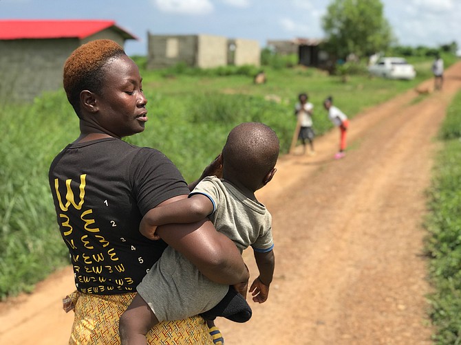 Sianneh Beyan, 32, and her 11-month-old son, Charles Allen, walk down a winding dirt road in Liberia to finish laundry.