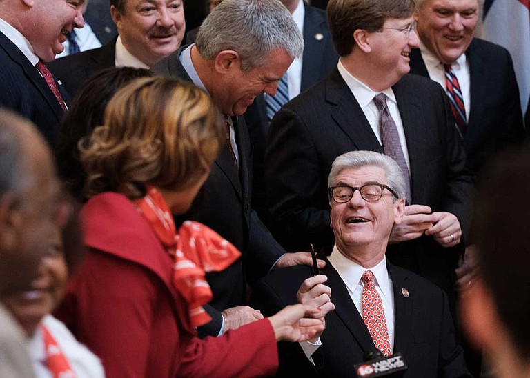 Surrounded by proud lawmakers, Mississippi Gov. Phil Bryant holds up a pen he used to sign the Mississippi Broadband Enabling Act in the State Capitol rotunda on Jan. 30, 2019.