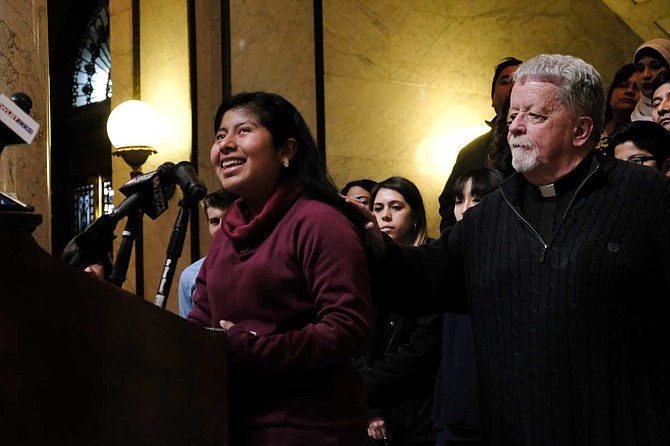 Mississippi Immigrants Rights Alliance Board of Directors member Father Jerry Tobin puts his hands on Yitzel, a young immigrant, as she sobbed from behind a podium in the Mississippi Capitol on Jan. 30. "I had to grow up really fast," she said.