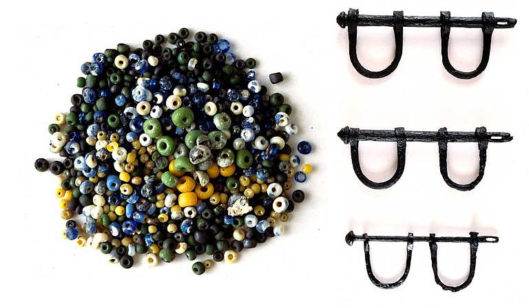 Tiny, colorful glass beads (left) found on the wreckage site of the Henrietta Marie slave ship were made in Europe. They were often used to trade for slaves. Aboard slave ships, Africans were forced to wear iron shackles (right), huddled below decks in the heat. Photo courtesy Corey Malcom/MDAH