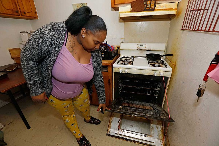 Destiny Johnson shows the broken door to her oven that she uses string to hold together, in her apartment in Cedarhurst Homes, a federally subsidized, low-income apartment complex in Natchez, Miss. The complex failed a health and safety inspection in each of the past three years. Upset with conditions, Johnson moved out in late March. Photo by Rogelio V. Solis via AP