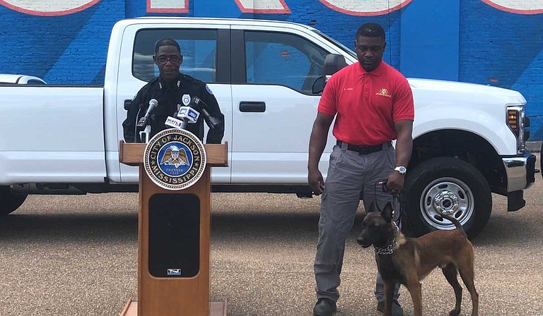 Officer Sam Brown (left) talks about the new bomb squad truck and equipment, while Aaron Allen (right), the canine handler, stands by with the new dog, Loki.