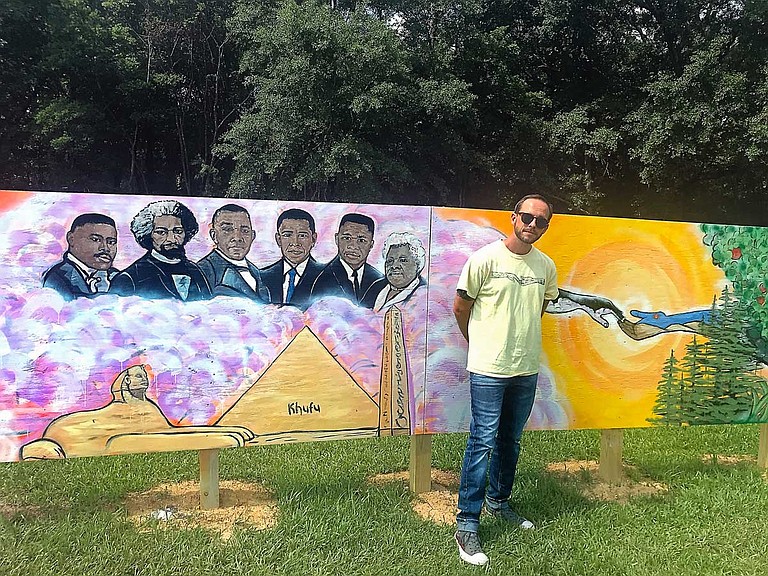 Eli Childers, a local Jackson artist, stands in the middle of the 72-foot mural along the fence of Wilkins Elementary School in south Jackson.