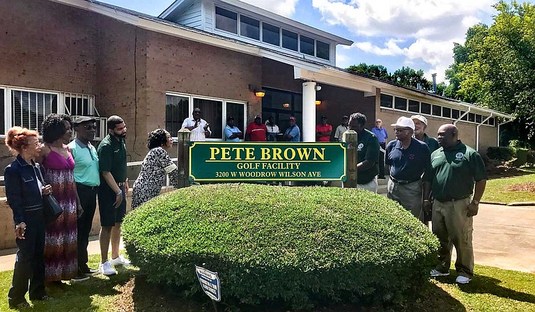 Margaret Brown (center left), Pete Brown’s wife, unveils a new sign, renaming Sonny Guy Golf Course to Pete Brown Golf Facility on May 23.