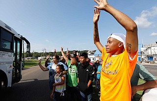 Friends, coworkers and family wave to one of several buses that are filled with detainees, following a U.S. Immigration raid at several Mississippi food processing plants, including this Koch Foods Inc., plant in Morton, Miss., Wednesday, Aug. 7, 2019. The early morning raids were part of a large-scale operation targeting owners as well as undocumented employees. Photo by Rogelio V. Solis via AP