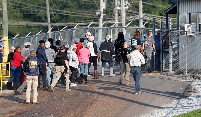 Workers filled three buses—two for men and one for women—at a Koch Foods Inc. plant in tiny Morton, 40 miles (64 kilometers) east of Jackson. They were taken to a military hangar to be processed for immigration violations. About 70 family, friends and residents waved goodbye and shouted, "Let them go! Let them go!" Later, two more buses arrived. Photo by Rogelio V. Solis via AP