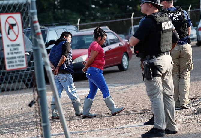 Two people are taken into custody at a Koch Foods Inc. plant in Morton, Miss., on Wednesday, Aug. 7, 2019. U.S. immigration officials raided several Mississippi food processing plants on Wednesday and signaled that the early-morning strikes were part of a large-scale operation targeting owners as well as employees. Photo by Rogelio V. Solis via AP