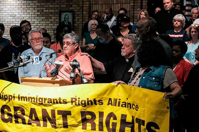 At a press conference on Aug. 8, Father Jeremy Tobin, a Catholic priest, puts his hand on the shoulder of Mississippi Immigrants Rights Alliance organizer Luis Espinoza, who has been working with immigrant families affected by the Aug. 7 ICE raids in Mississippi. Photo by Ashton Pittman