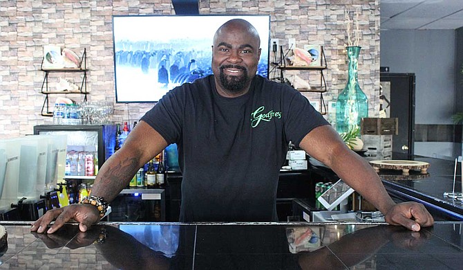 Chef and restaurant owner Godfrey Morgan stands behind the bar of his restaurant, Godfrey’s, which serves cuisine from southern, Asian and Caribbean cultures. Photo by Aliyah Veal