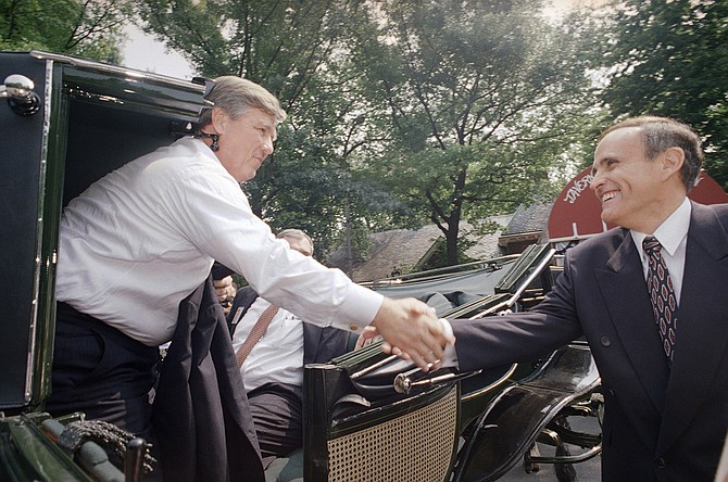 New York City Mayor Rudolph Giuliani, right, shakes hands with Haley Barbour, chairman of the Republican National Committee. Now, Giuliani is Donald Trump's attorney, and Kurt Volker, an associate at Barbour's lobbying firm, BGR Group, are central figures in a presidential impeachment inquiry. (AP Photo/Joseane Daher)