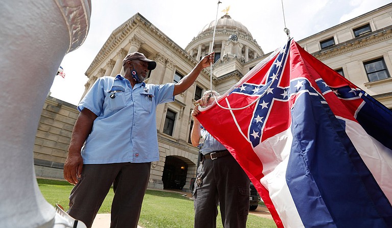 Mississippi Department of Finance and Administration employees Willie Townsend, left, and Joe Brown, attach a Mississippi state flag to the harness before raising it over the Capitol grounds in Jackson, Miss., Tuesday, June 30, 2020. The two men raised about 100 flags, provided by the Secretary of State's office, for people or organizations that purchased a state flag that flew over the grounds. Gov. Tate Reeves will sign a bill Tuesday evening retiring the last state flag with the Confederate battle emblem during a ceremony at the Governor's Mansion. Upon the governor signing the bill, the flag will lose its official status. Photo courtesy Rogelio V. Solis via AP