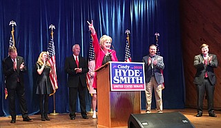 Hyde-Smith flashes victory sign as she addressed supporters Tuesday night at the Mississippi Agriculture and Forestry Museum. Congressional District 2 Representative Micheal Guest, his wife, Hyde-Smith's husband Micheal, a guest and Gov. Tate Reeves shared the stage with her. Photo by Kayode Crown