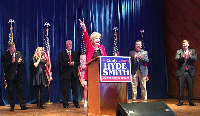 Hyde-Smith flashes victory sign as she addressed supporters Tuesday night at the Mississippi Agriculture and Forestry Museum. Congressional District 2 Representative Micheal Guest, his wife, Hyde-Smith's husband Micheal, a guest and Gov. Tate Reeves shared the stage with her. Photo by Kayode Crown
