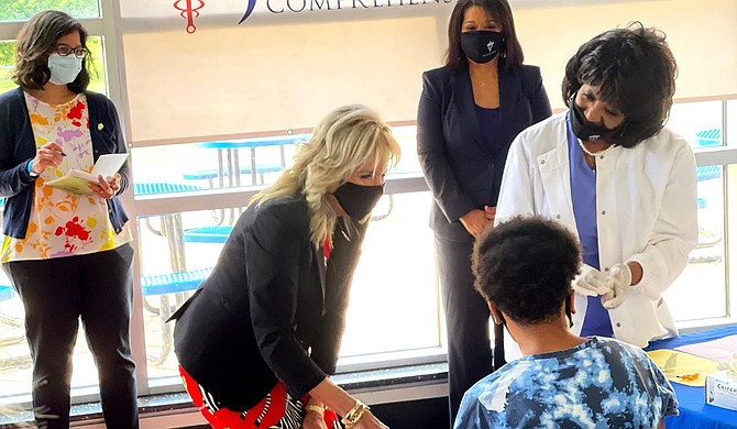 Dr. Jill Biden holds Christian Lyles, 13, who was afraid of needles, as nurse Maggie Bass administers a vaccine to him on Tuesday, June 22, at Jackson State University. The first lady was in Jackson to draw attention to the need for the people to get vaccinated. Photo by Kayode Crown
