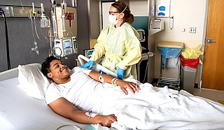 Registered Nurse Helen Ann Campbell lightens the mood with a joke while checking on 16-year-old COVID-19 patient Keelyn Green in Blair E. Batson Tower of Children's of Mississippi Thursday, Aug. 12, 2021. The Jim Hill High School senior was unvaccinated when he tested positive for COVID-19 in early August 2021. Photo courtesy UMMC