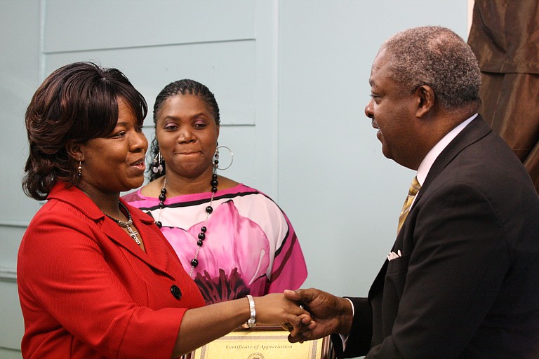 Mayor Harvey Johnson Jr., right, presents Shuntel's Boutique owner Yalonda Gladney, left, with a certificate of appreciation at the store's grand opening today.