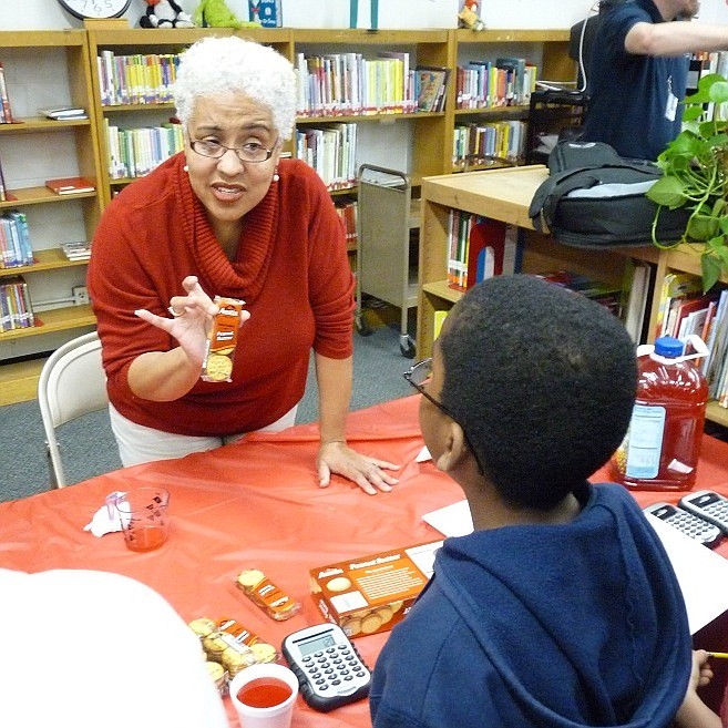 Thea Faulkner helps a student at Casey Elementary School learn math by calculating how many snacks he can buy for a certain amount of money.