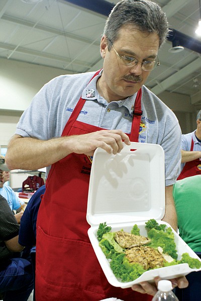 Table captain John Lacourrége displays a plate of barbecue chicken for judging at the Kansas City Barbeque Society judges class at St. Francis of Assisi in Madison.